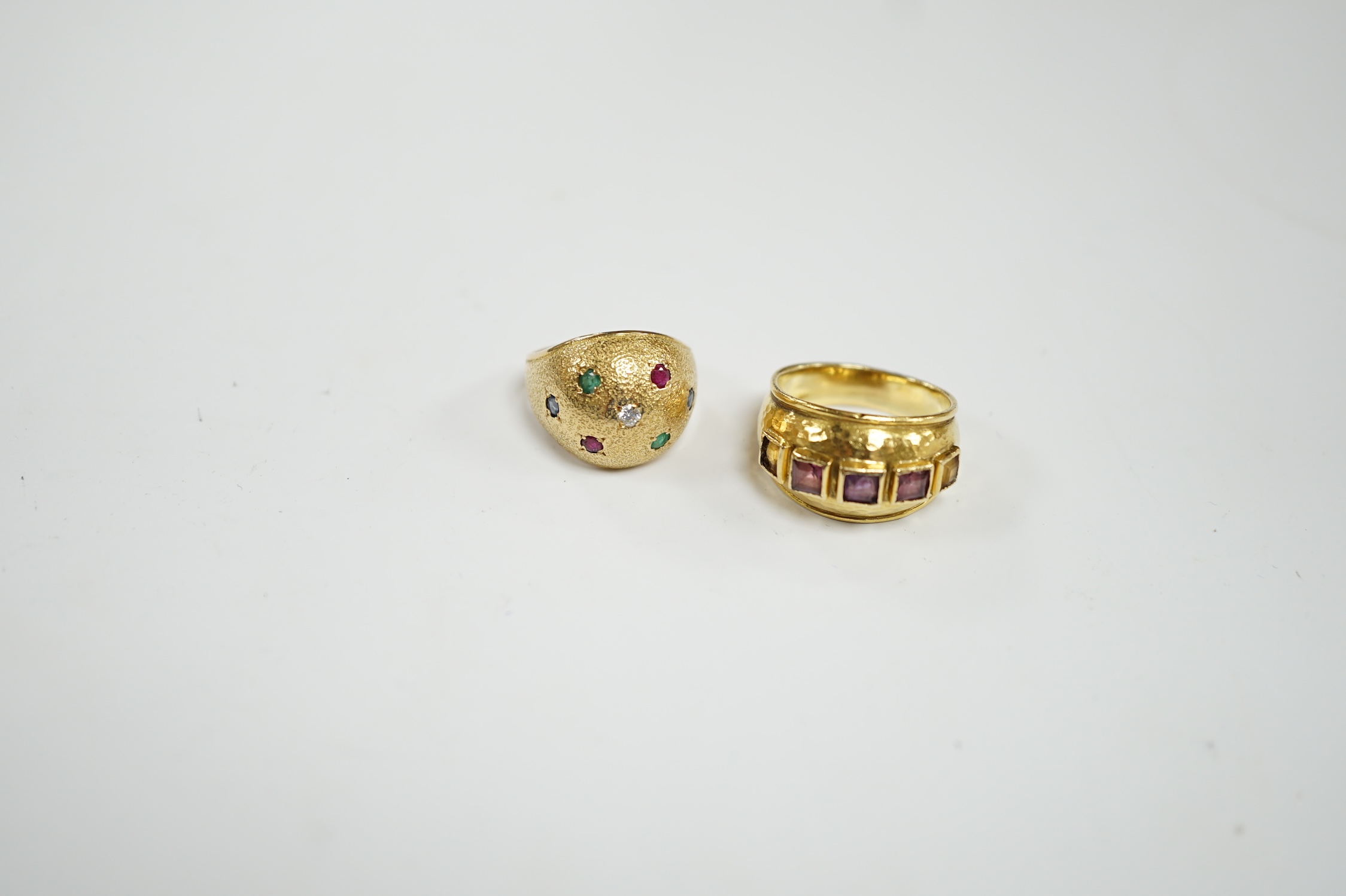A textured yellow metal, emerald, ruby and diamond set domed ring, size K, together with a stylish yellow metal and graduated square cut amethyst set five stone ring, size M, gross weight 13.1 grams.